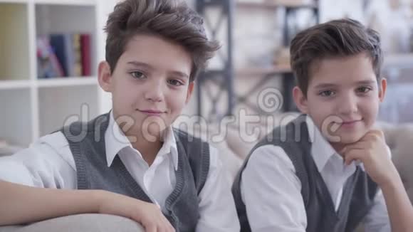 特写肖像英俊的小白种人双胞胎兄弟看着镜头微笑阳性的黑发男孩视频的预览图
