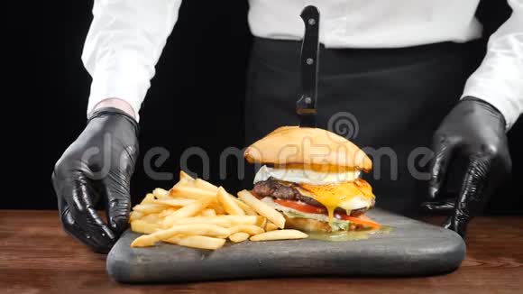 厨师拿着棕色的切割板和新鲜的汉堡和炸薯条慢慢地把它放在桌子上男性厨师视频的预览图