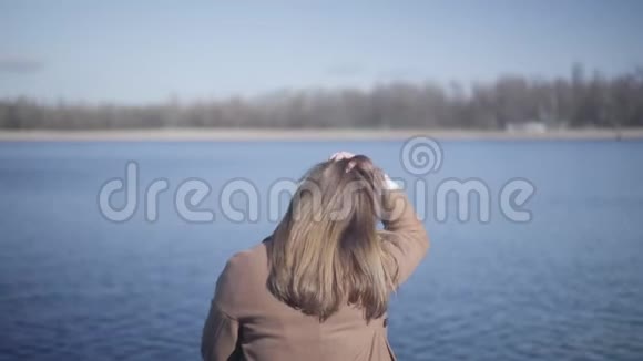 在户外平静的蓝色波浪背景下深色头发的女孩的后景年轻的白人女性视频的预览图