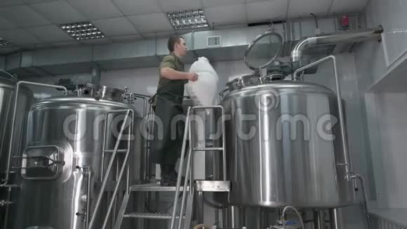 工人男制啤酒厂将粉碎的麦芽倒入啤酒罐中生产工艺啤酒视频的预览图