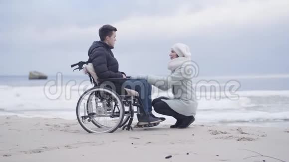 年轻的女人坐在轮椅上的男孩面前说话母亲或支持无效投标视频的预览图