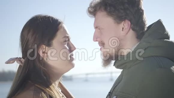 一个满脸笑容的白人男人戴着鼻环胖乎乎的黑发女人在河岸擦鼻子侧视视频的预览图