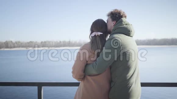 在河岸亲吻女友和微笑的年轻白种人男人的后景新婚夫妇在户外约会视频的预览图