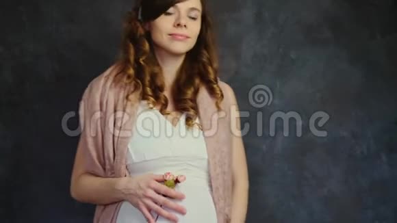 美丽的孕妇抚摸着她的腹部黑暗背景下的女性准妈妈母亲关爱观念视频的预览图