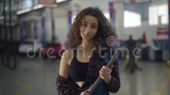 积极的年轻白人妇女站在汽车修理店扳手的肖像漂亮的女汽车修理工视频的预览图