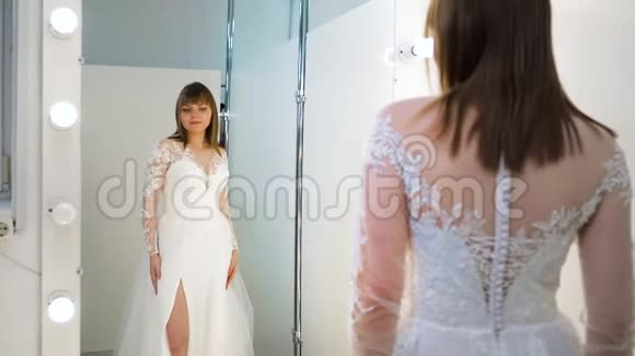 漂亮新娘在沙龙里穿婚纱时的镜子反射视频的预览图