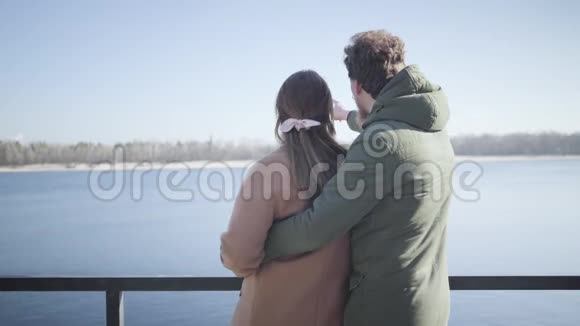 阳光明媚的秋日幸福的年轻夫妇在河岸边聊天高加索男人拥抱女友视频的预览图