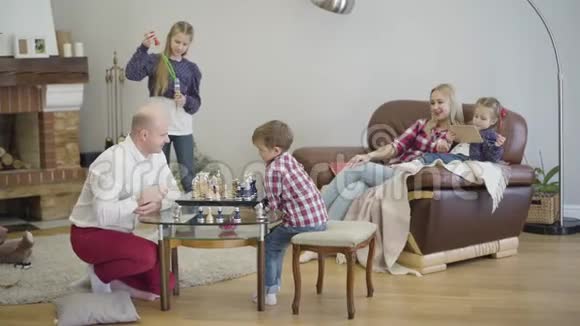 快乐的大家庭周末一起在室内度过的肖像父子下棋大女儿吹视频的预览图