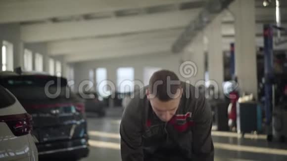 专业男车修工抬车轮胎和看镜头的肖像摄像头正对着视频的预览图