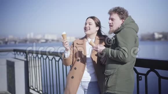 年轻微笑的高加索夫妇在户外聊天和吃冰淇淋的肖像很漂亮的黑发女孩视频的预览图