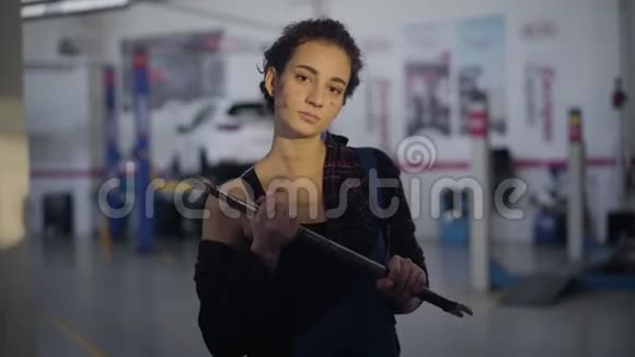 一幅自信的黑种人白种人女人的肖像棕色的眼睛在汽车修理店里摆着扳手专业人员视频的预览图
