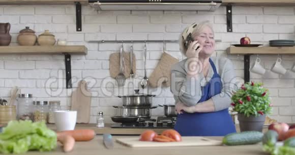 积极的高级退休人员在家厨房打电话成熟开朗的白种人妇女站着的肖像视频的预览图
