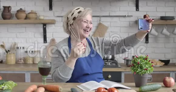 在自拍相机上用威士忌和酒杯摆姿势笑高白种人女人的肖像成熟的积极退休人员视频的预览图