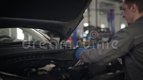 男性白种人汽车机械师把发动机空气过滤器放进汽车里穿工作服的职业男性视频的预览图