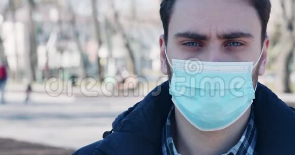 戴医疗防护面具的男子站在城市公园视频的预览图