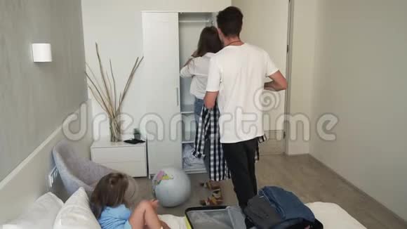 快乐的白种人一家人和他们的小女儿度假回来在新房子里打开黄色的手提箱视频的预览图