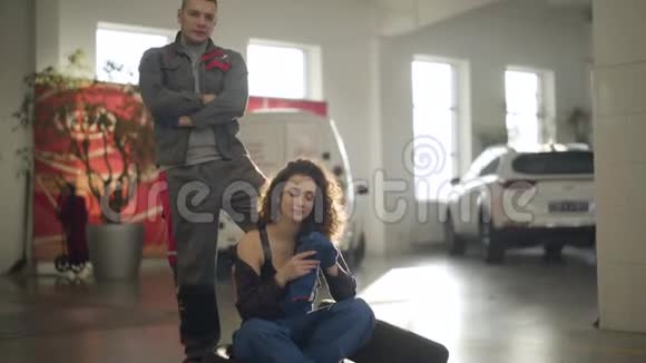 年轻可爱的高加索女人脱下手套看着镜头她的男性同事站在后面二视频的预览图