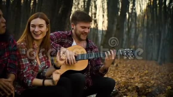 秋天森林里快乐的游客用吉他唱歌视频的预览图