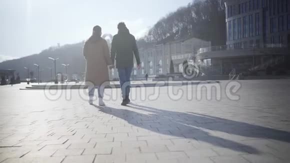 一对年轻的幸福夫妇在城市广场漫步白人男女在阳光明媚的秋天散步视频的预览图