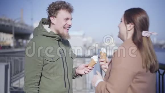 快乐的年轻女人用冰淇淋抚摸男人鼻子笑着积极的高加索夫妇约会的肖像视频的预览图