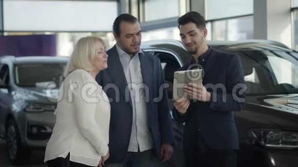 年轻英俊的高加索男子与平板电脑咨询客户在汽车经销商的肖像成人客户视频的预览图