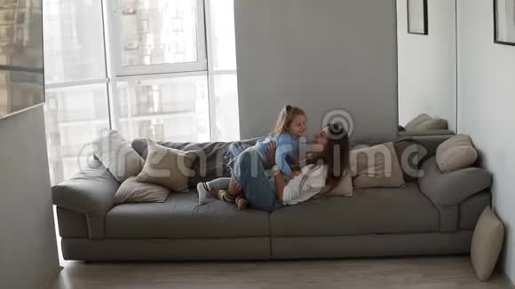 幸福的家庭母亲和孩子女儿一起在沙发上玩得开心年轻女子挠痒痒引进来视频的预览图