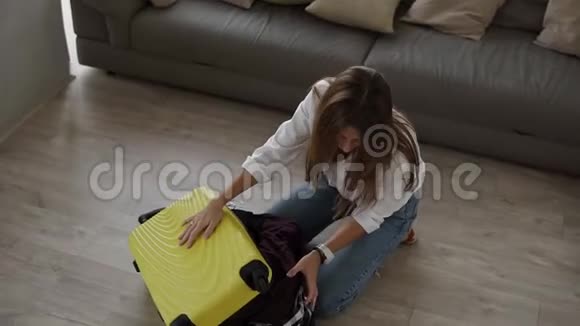准备旅行包年轻女子收拾行李绝望地试图关上手提箱关上拉链视频的预览图