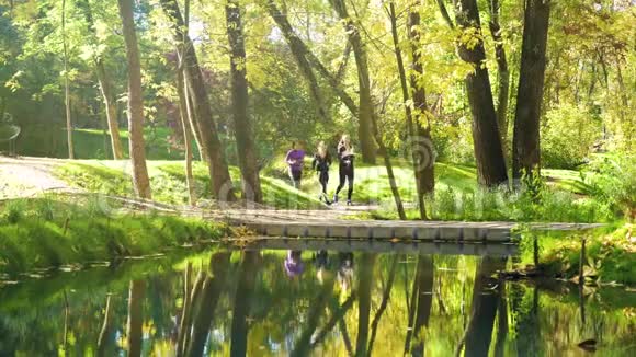 城市公园里的女运动员在河上的桥上慢跑视频的预览图