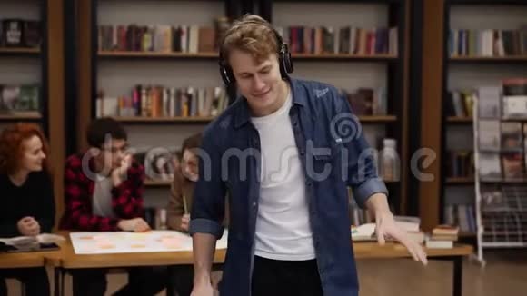 穿着牛仔衬衫的英俊兴奋的欧洲男子一边听着耳机里的音乐一边表演富有表现力的舞蹈视频的预览图