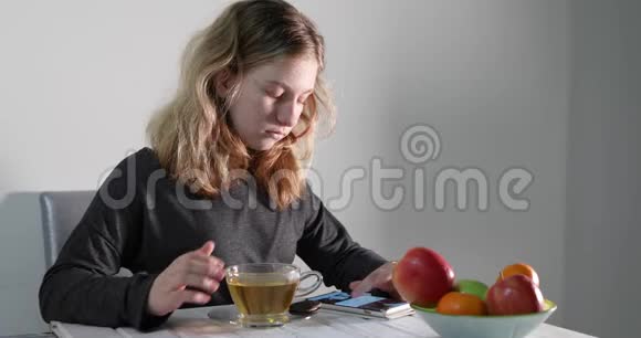 一个十几岁的女孩看着一部手机端着饼干喝茶视频的预览图