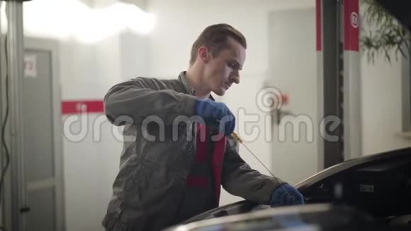 专业的白种人汽车机械师检查机油在修理厂进行汽车检查的严肃青年视频的预览图