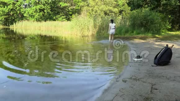 女徒步旅行者在夏天散步后在湖中放松视频的预览图