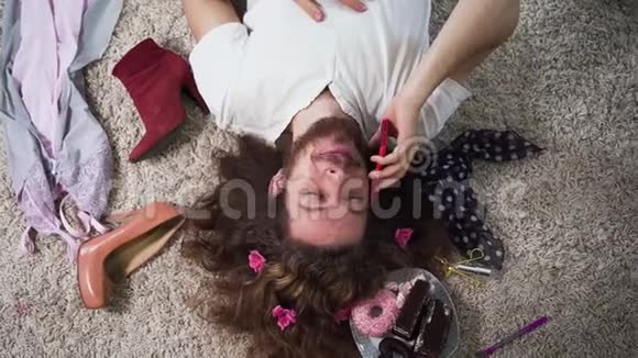 俯视着快乐的白种人躺在柔软的地毯上在电话里交谈二元性别男子画像视频的预览图