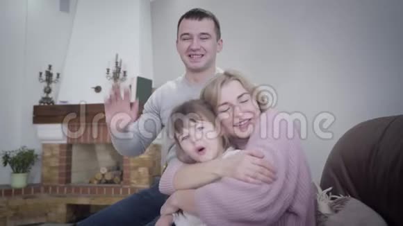 年轻友好的高加索男人女人和小女孩坐在扶手椅上拥抱微笑快乐的人们在室内摆姿势视频的预览图
