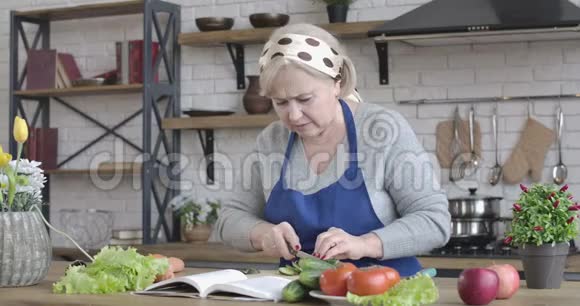 成熟的白种人女人在家里用菜刀切手指做沙拉退休人员准备的肖像视频的预览图