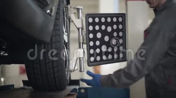 男性白种人汽车机械师的特写镜头来到汽车上调整车轮上的设备然后离开专业人员视频的预览图