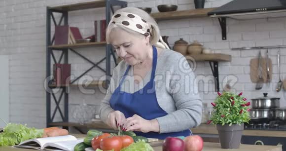 阳性白种人女性退休人员切黄瓜沙拉和品尝一片的侧面观察成熟的肖像视频的预览图