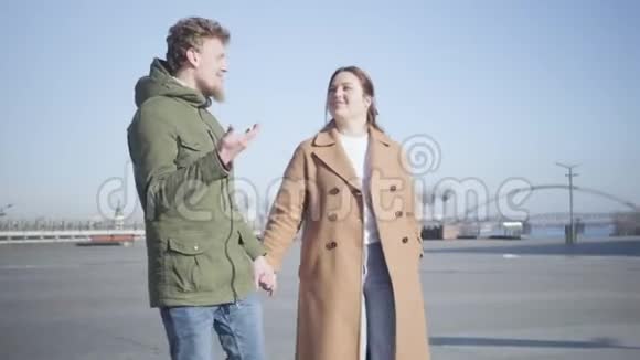年轻微笑的白种人男女在户外散步时谈话的肖像城市广场上的幸福情侣约会视频的预览图