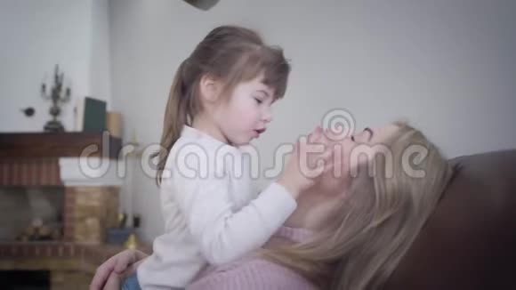 一个可爱的小白种人黑发女孩在家里和漂亮的金发母亲玩快乐的年轻女子视频的预览图