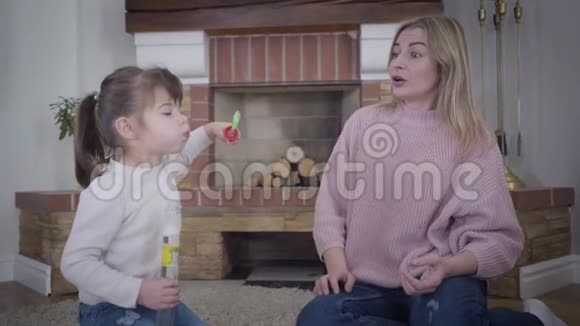 美丽的年轻白种人女人帮助小可爱的女孩吹肥皂泡开朗的妈妈周末视频的预览图