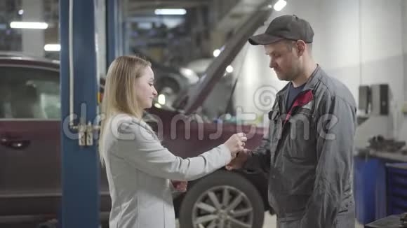年轻的高加索女人把车钥匙递给维修工程师摇了摇手充满自信的女士离开视频的预览图
