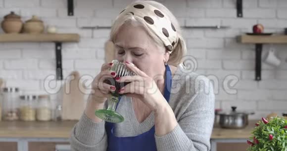 中年白种人女人在厨房里喝红酒和说话的特写肖像资深家庭主妇视频的预览图