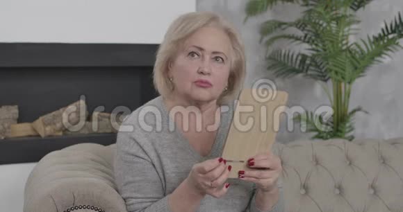 优雅的高级女人用镜子检查脸上的皱纹担忧的中年女性退休者的画像视频的预览图