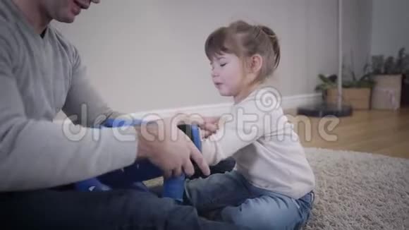 年轻的白种人父亲把拳击手套戴在小女儿手上快乐的漂亮女孩和成年男人视频的预览图