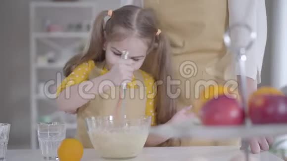 快乐的黑发小女孩敲打烘焙原料的肖像可爱的白种人孙女帮助成年女性视频的预览图