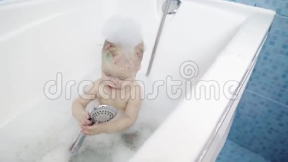 一个小女孩在用泡沫和肥皂泡洗澡一个水痘女孩在浴室洗澡视频的预览图