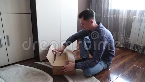 一个英俊的男人用吸尘器打开一个包裹一个男人从中国打开一个包裹视频的预览图