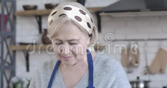 在室内做饭的漂亮白人女性的特写脸棕色眼睛开朗的退休女性吃黄瓜视频的预览图