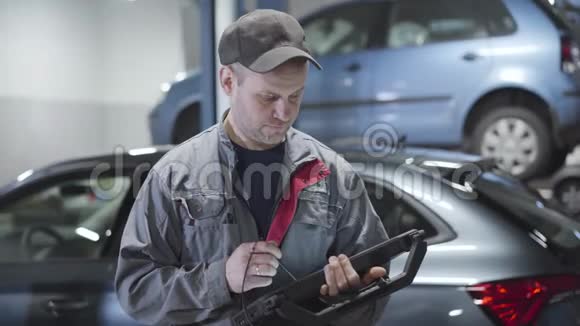 白种人成年男子使用电脑和环顾汽车修理店的肖像专业汽车维修视频的预览图