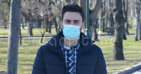 站在城市公园里戴着医用防护面具的年轻人视频的预览图